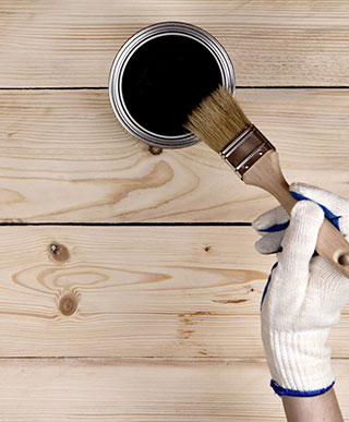 Close-up of staining a deck with paint brush