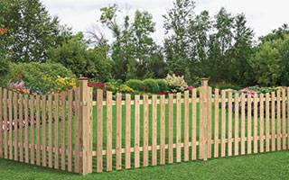 Spaced Picket Concave Top Pressure-Treated Wood Fence with flowers in background