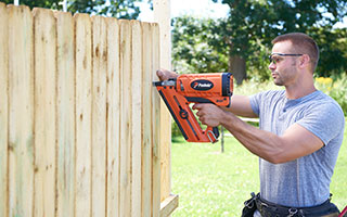 Main using nail gun to construct wood fence