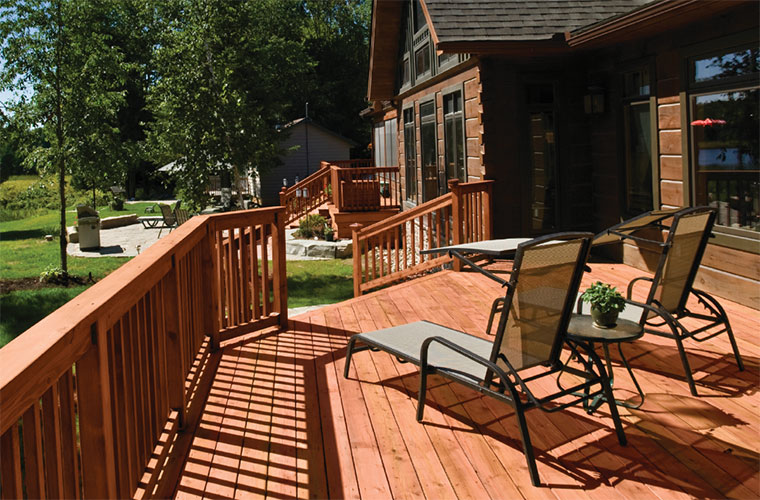 Log cabin with ProWood pressure-treated wood decking and railing in Cedar Tone